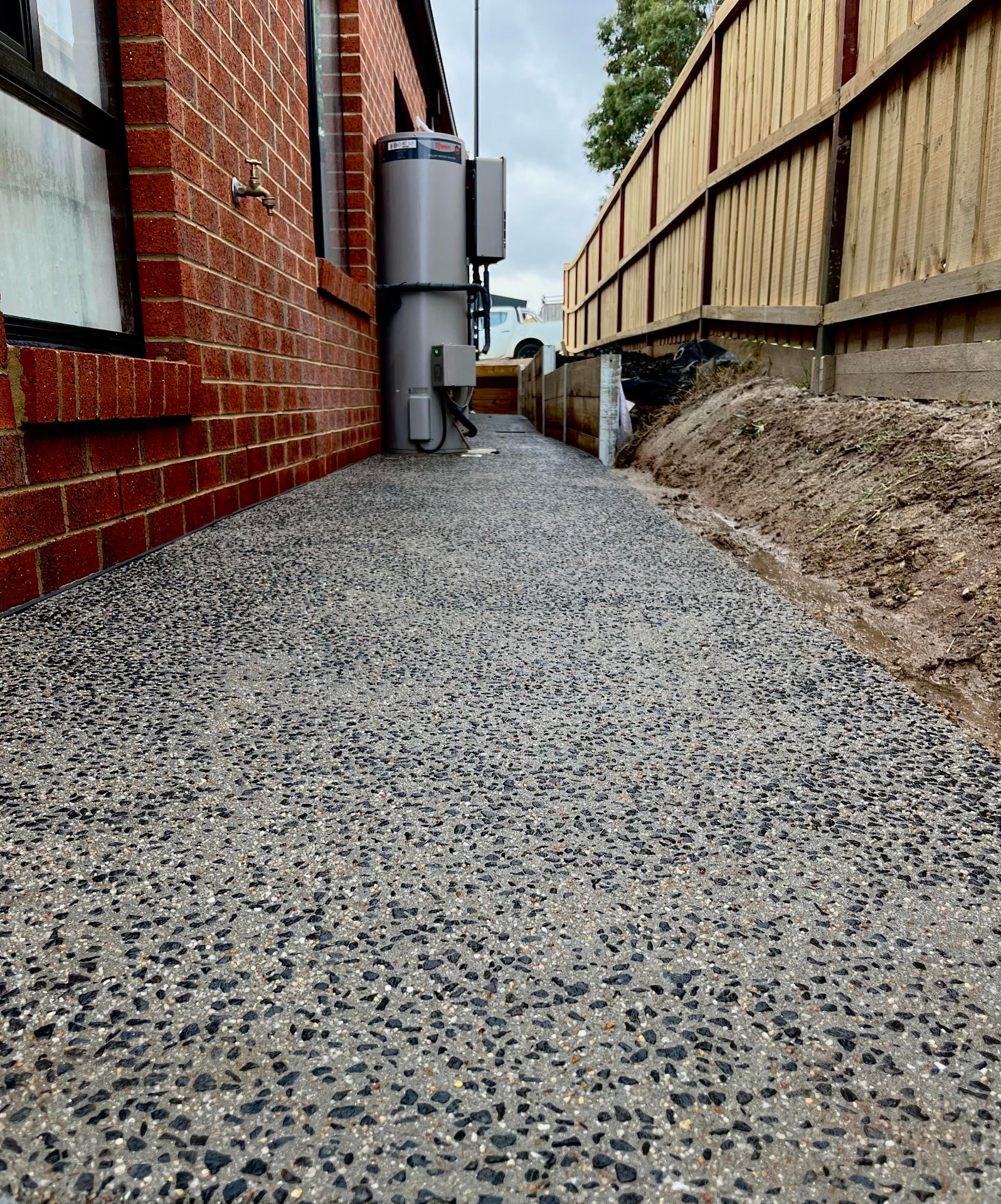 Exposed aggregate side path — Narrow-access side path with dark aggregate finish and clean edges