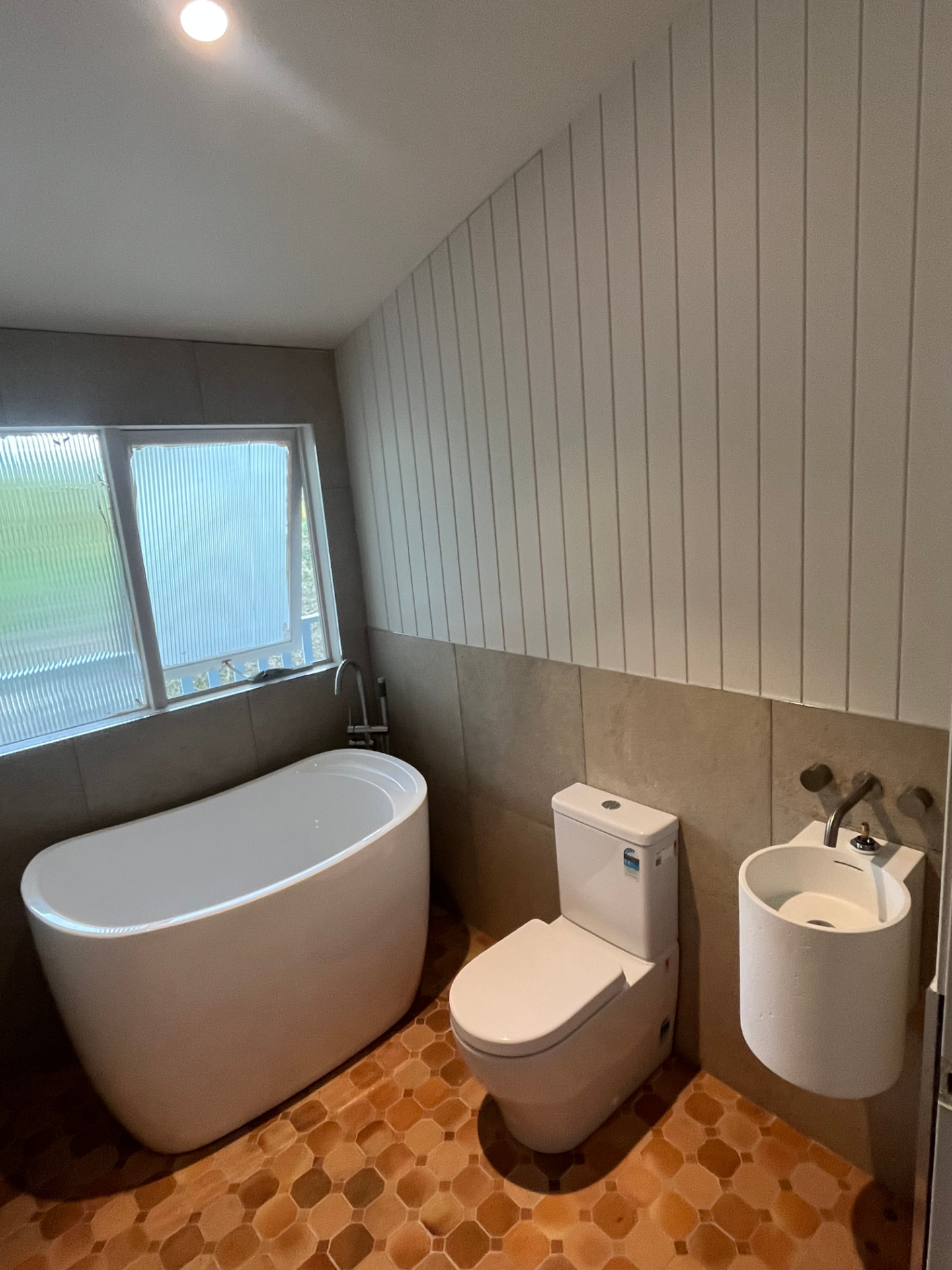 Powder room with Japanese soaking bath — Compact powder room fit-off with freestanding Japanese soaking tub and feature floor tile