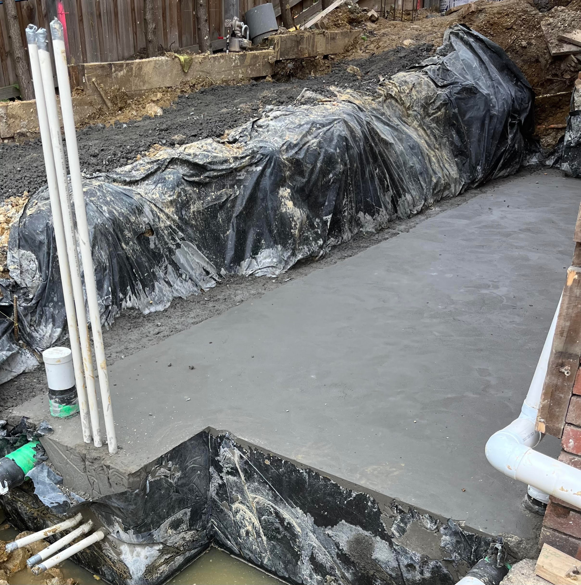 Extension slab pour — Reinforced extension slab poured over vapour barrier with plumbing and conduit set in place