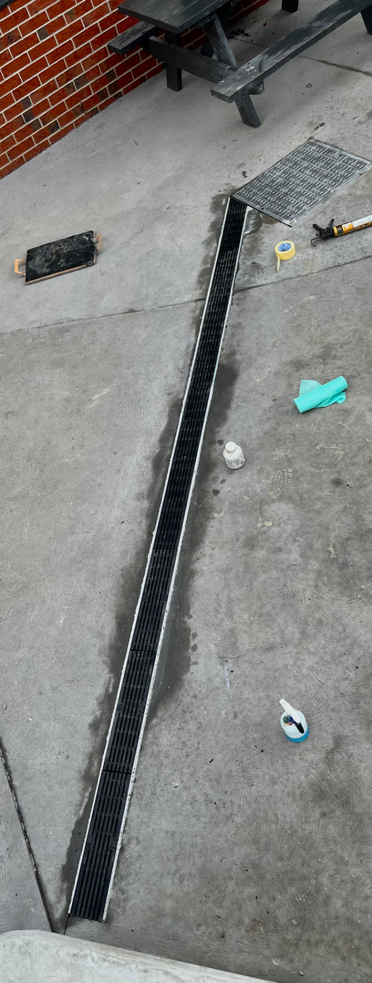 Strip drain installation — Linear strip drain cut into an existing slab and sealed flush for surface water
