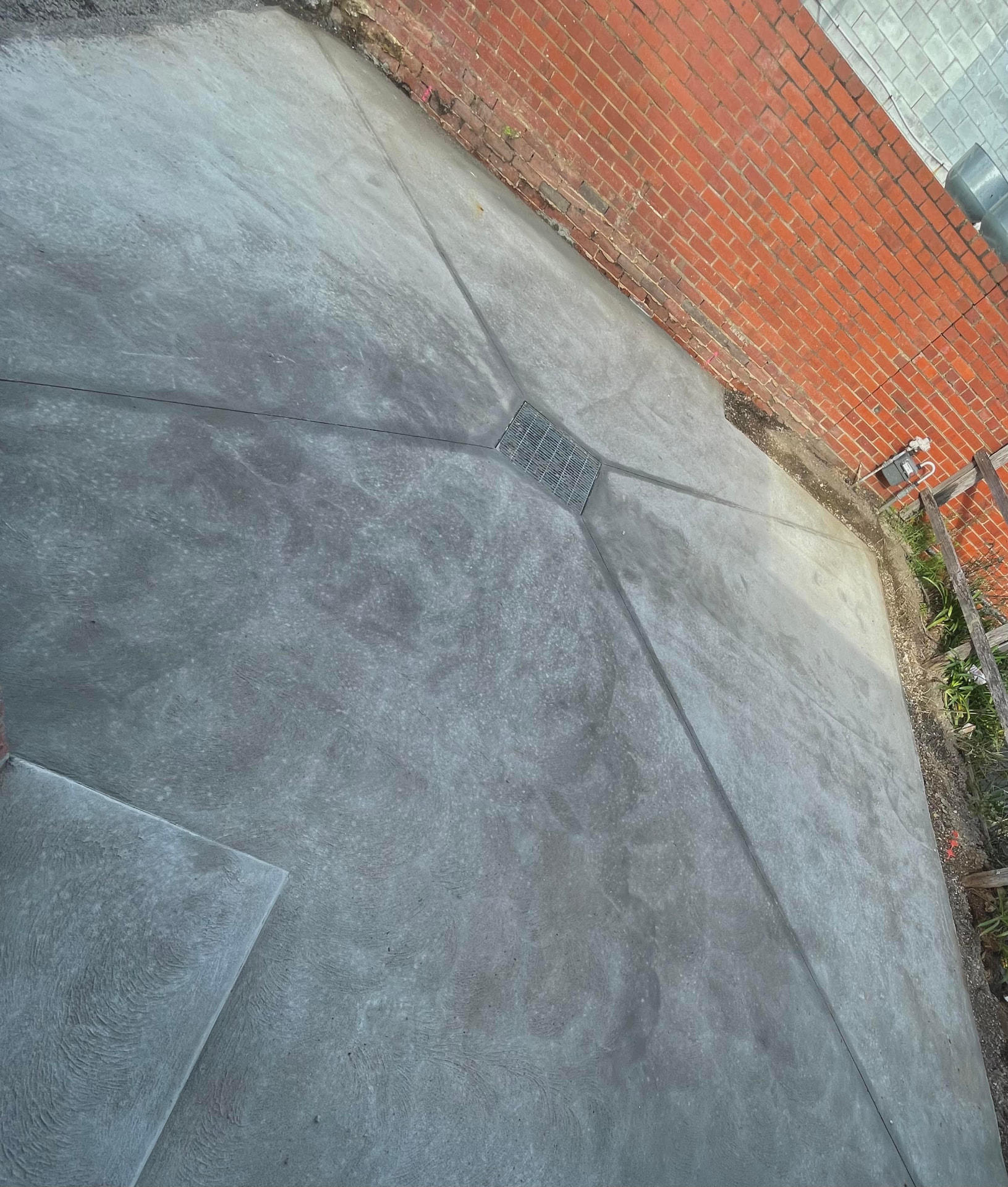 Plain concrete courtyard with stipple finish and drainage grate