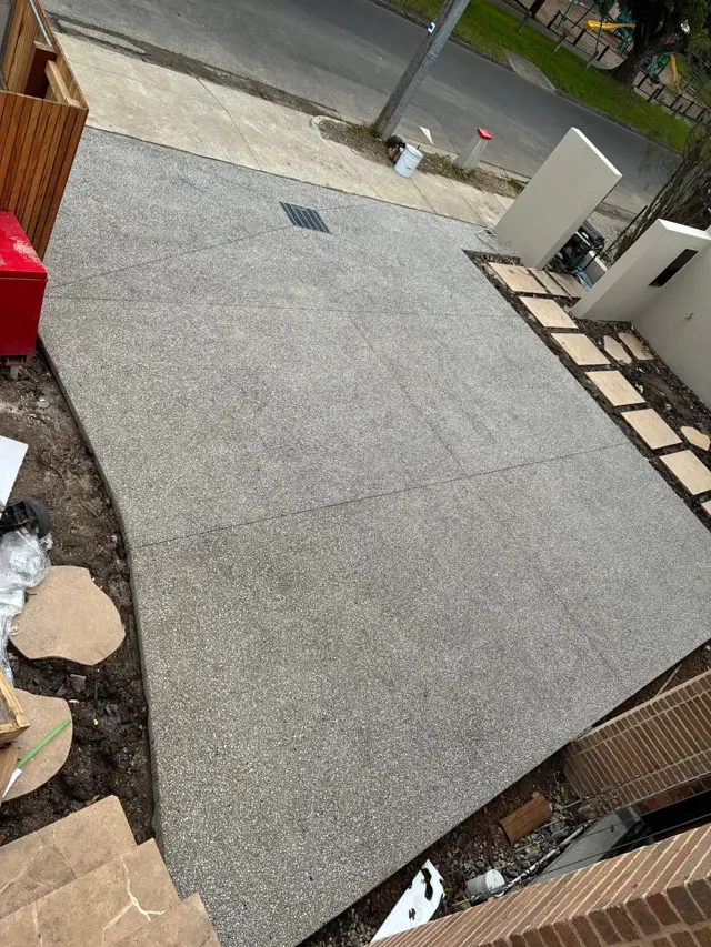 Exposed aggregate driveway — Wide driveway with crossover access, grated drainage point and saw-cut control joints