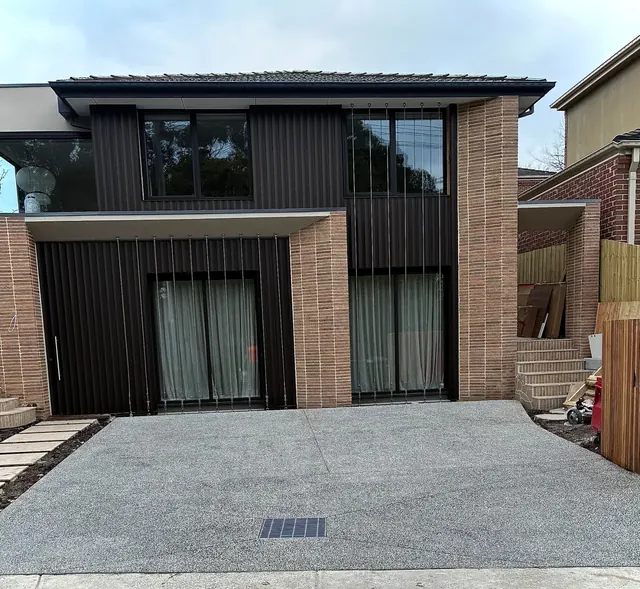 Exposed aggregate driveway with integrated grate — Full front driveway pour with integrated stormwater grate and clean saw-cut joints