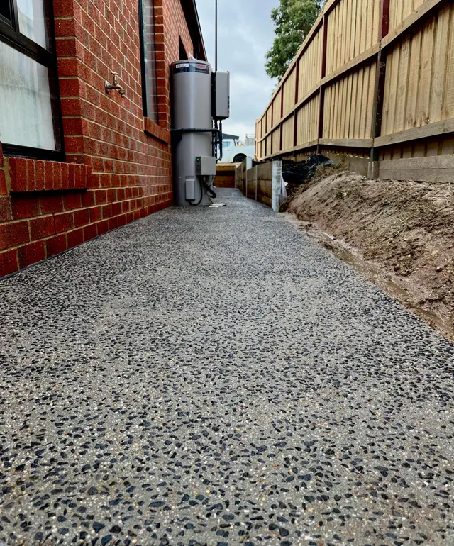 Exposed aggregate side path — Narrow-access side path with dark aggregate finish and clean edges